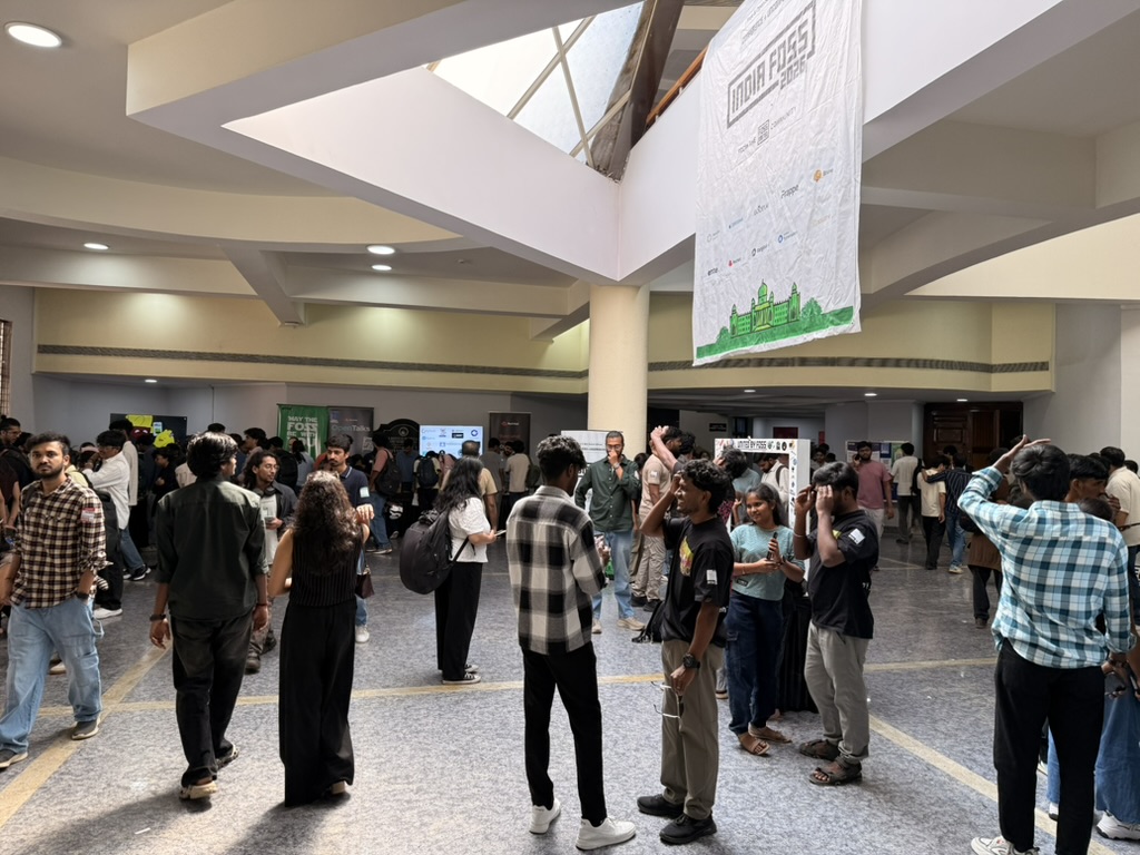 Attendees in the NIMHANS Convention Centre foyer under a large IndiaFOSS 2026 banner