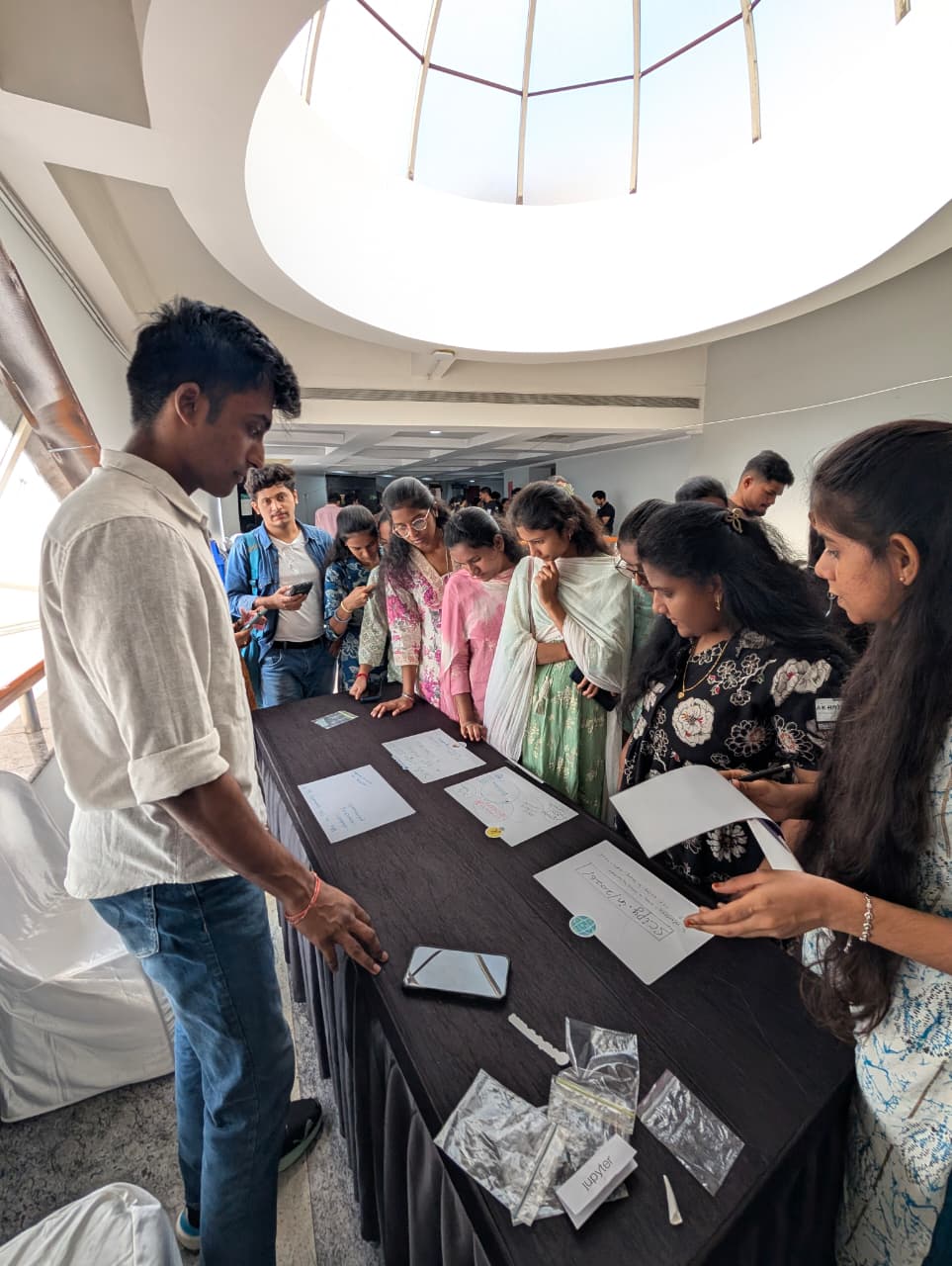 Srihari at the SciPy India booth with a group of attendees reading the handwritten signs on the table